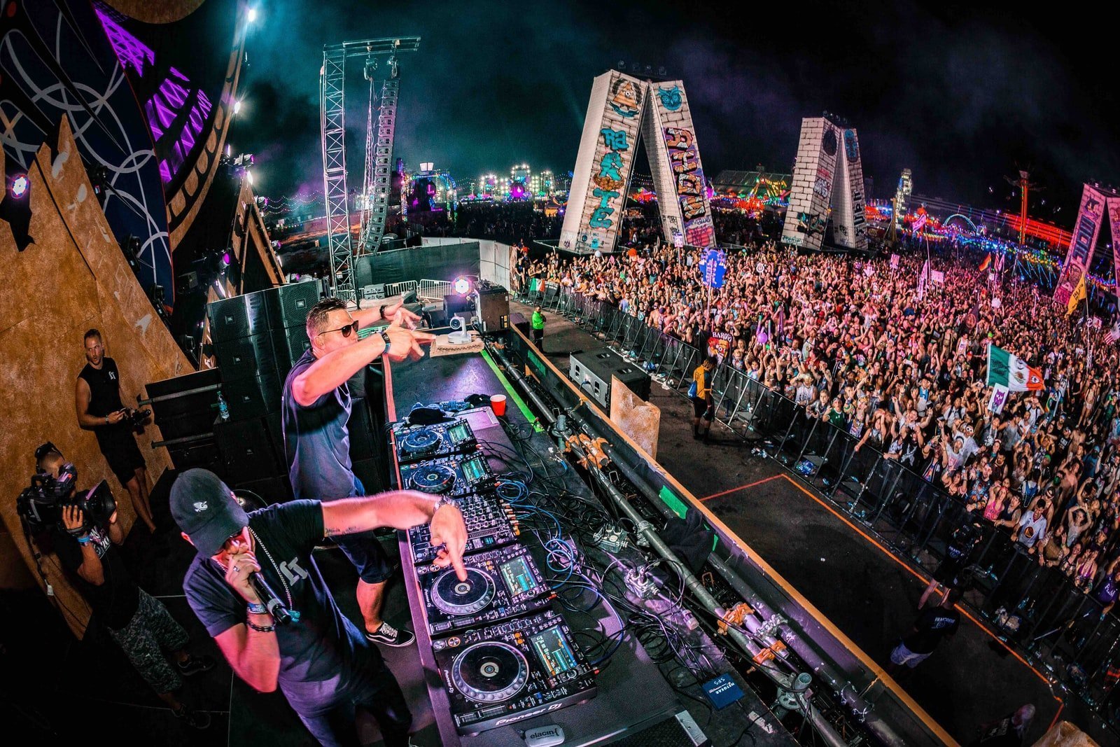 two men playing DJ controllers at night time